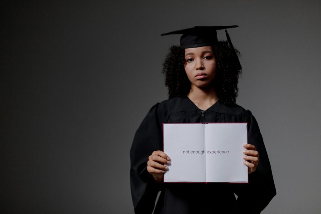 Young graduate holding a book with 'not enough experience' message, symbolizing job hunt difficulties.